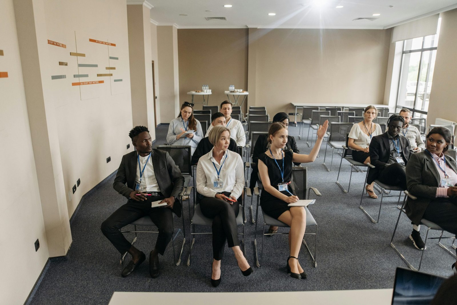 Participants in a conference looking at a female participant raising her hand