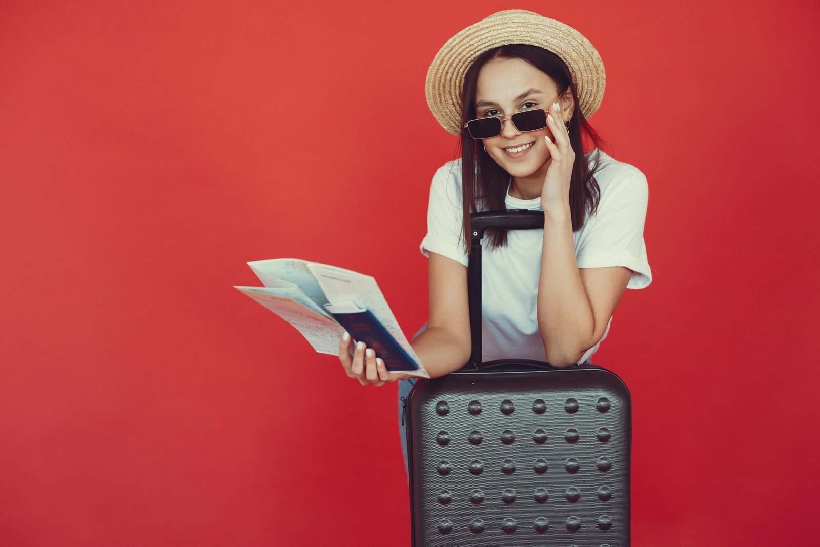 Picture of a Cheerful female tourist checking tickets on red background