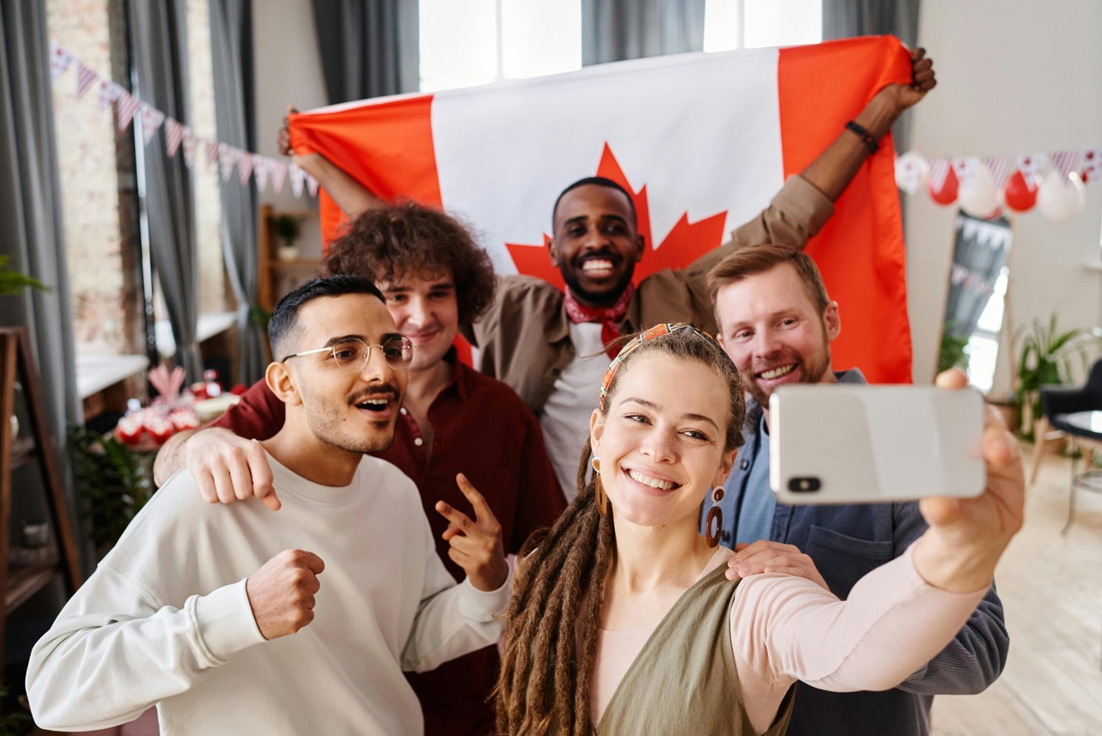 Picture of a group of friends taking selfie while one holds a large Canadian flag