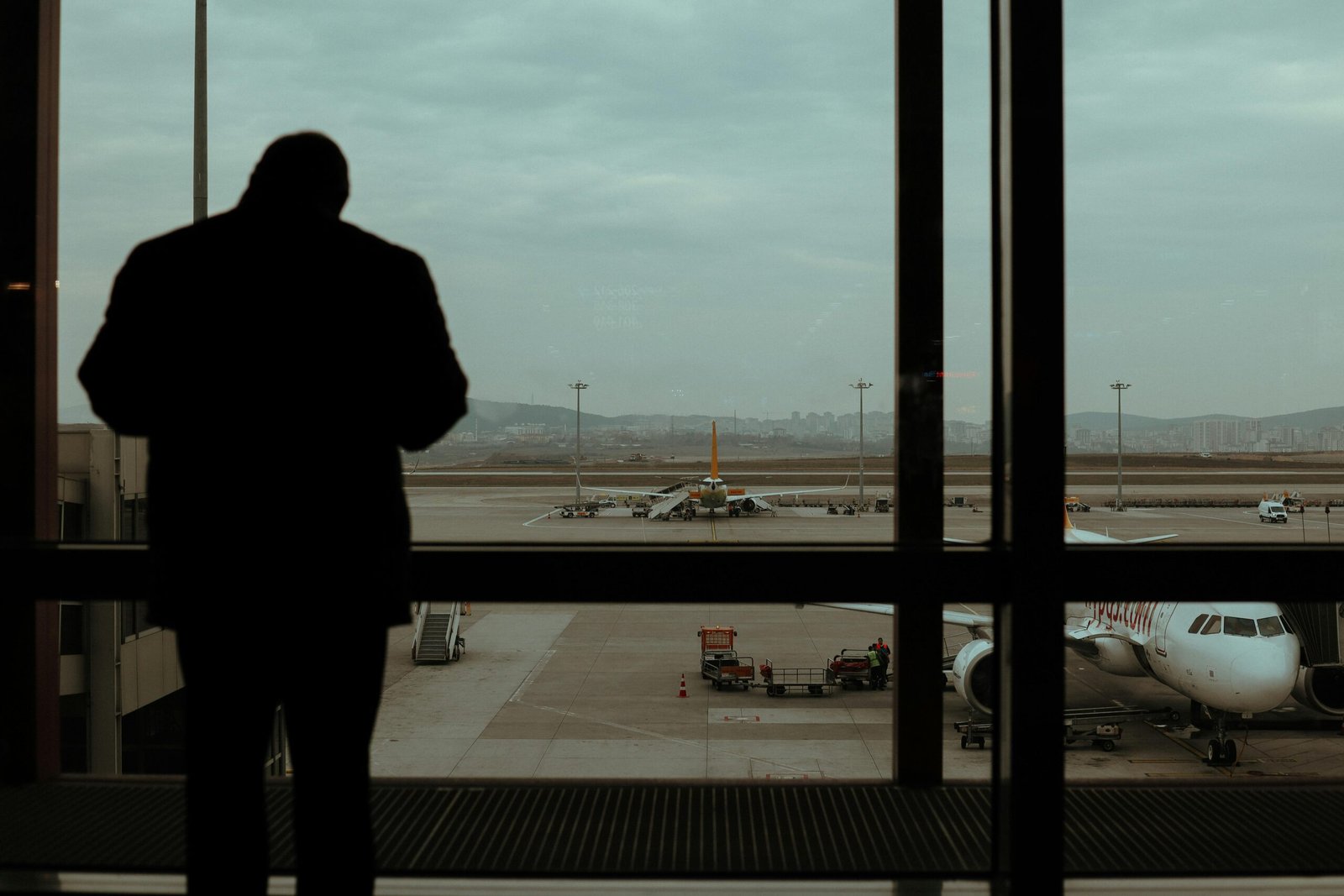 Silhouette of a traveler Standing Near Glass Windows of an airport waiting for his flight