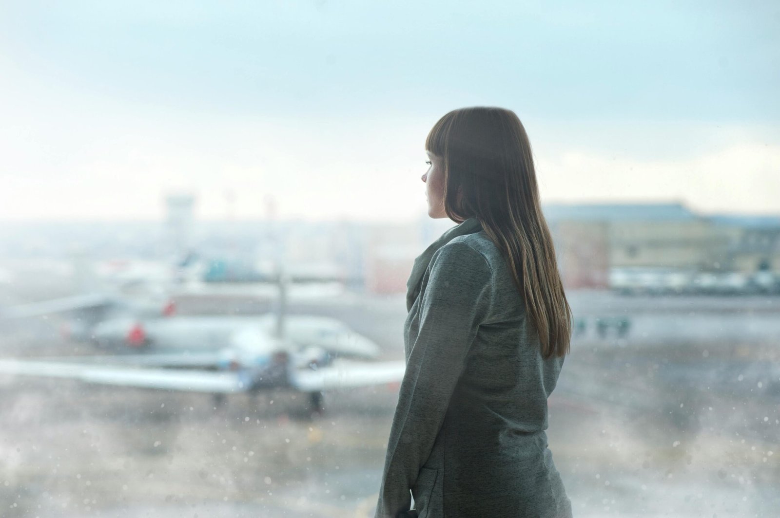 A lady Looking Through the Glass Wall an airport hallway