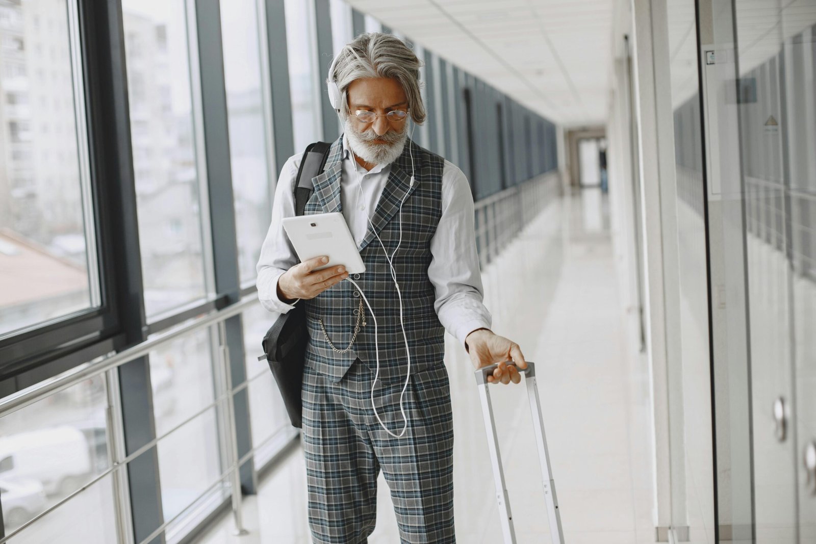 Bearded Man Holding a Tablet on his right hand and his luggage on his left hand