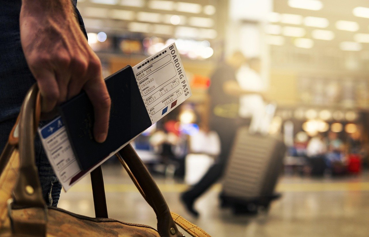 A man's hand holding his passport and Boarding pass in an airport