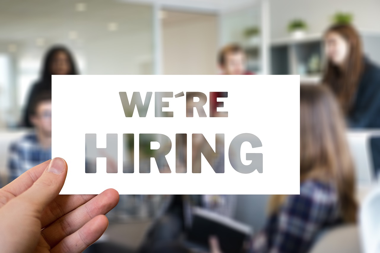 An employer holding a note that says "We are hiring"